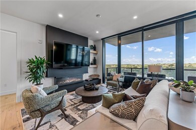 Living room with floor to ceiling windows, wood finished floors, a glass covered fireplace, and recessed lighting