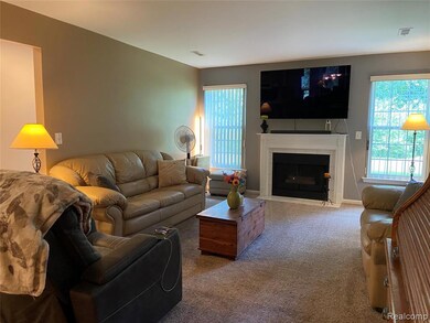 Living area featuring carpet flooring, plenty of natural light, and a tiled fireplace