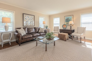 Living area with hardwood floors, healthy amount of natural light, and crown molding