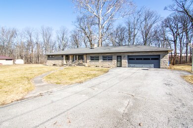 view of front facade with stone siding, driveway, an attached garage, and a front lawn