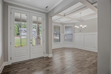 Foyer featuring french doors, a chandelier, beam ceiling, dark wood-style floors, and coffered ceiling