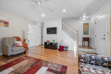 Living area with light wood-type flooring, stairway, recessed lighting, and a ceiling fan