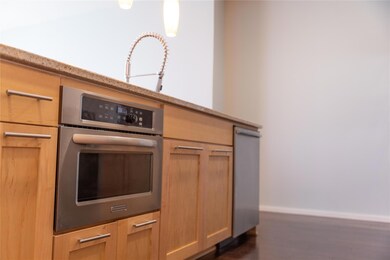 Kitchen with light brown cabinetry, oven, and dar