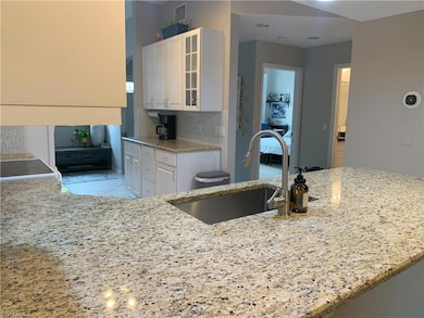 Kitchen with light stone counters, white cabinets,