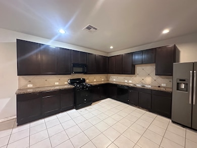 Spacious kitchen with dark cabinetry, tiled backsp