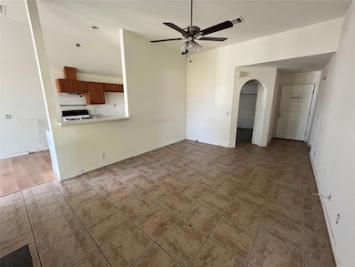 Unfurnished living room with arched walkways, ceiling fan, and dark tile patterned floors