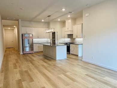 Kitchen with stainless steel appliances, decorative light fixtures, decorative backsplash, light wood finished floors, and recessed lighting