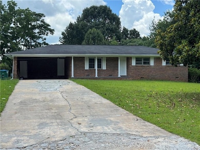 Ranch-style house featuring concrete driveway, a front yard, crawl space, a carport, and brick siding