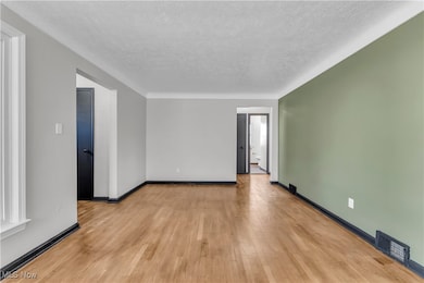 Unfurnished room featuring light wood-style flooring and a textured ceiling