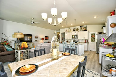 Dining room featuring a chandelier, vaulted ceiling, ceiling fan, recessed lighting, and light wood-style floors