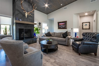 Living room with wood finished floors, a tiled fireplace, wood ceiling, recessed lighting, and a towering ceiling