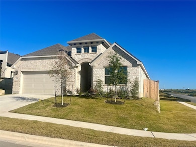 French country style house with stone siding, concrete driveway, an attached garage, brick siding, and roof with shingles