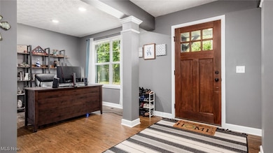 Home office with a textured ceiling, healthy amount of natural light, wood finished floors, recessed lighting, and ornate columns