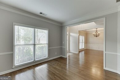 Spare room with crown molding, healthy amount of natural light, a chandelier, and wood finished floors