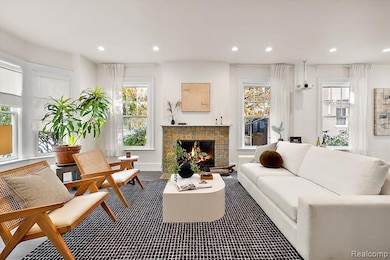 Living room with a natural fireplace, plenty of natural light, recessed lighting, and 5-inch plank solid oak hardwood floors