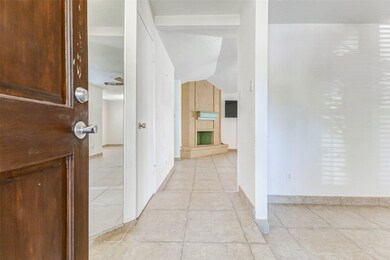 Inviting entryway with neutral tile flooring and a view into the spacious living area featuring a cozy fireplace as the focal point.