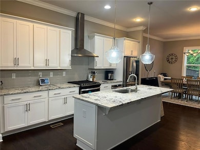Kitchen with wall chimney exhaust hood, stainless steel refrigerator with ice dispenser, a sink, black gas range, and tasteful backsplash