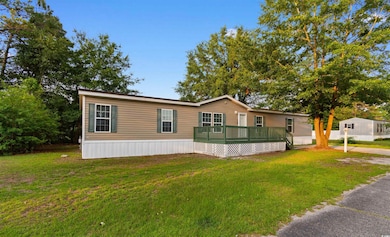 Manufactured / mobile home featuring a front lawn and a wooden deck