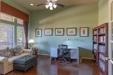 Bright and functional office with hardwood floors and front-facing windows.