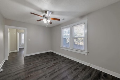 Empty room with dark hardwood / wood-style flooring, ceiling fan, and a textured ceiling