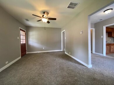 Empty room with ceiling fan, dark colored carpet, baseboards, and a sink