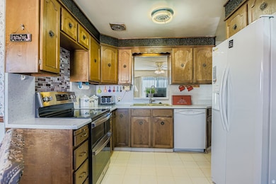Kitchen featuring white appliances, light countertops, brown cabinets, and ceiling fan