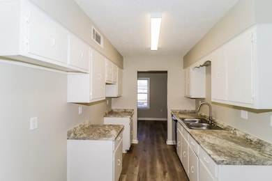 Kitchen featuring white cabinetry, light countertops, and dark wood-type flooring