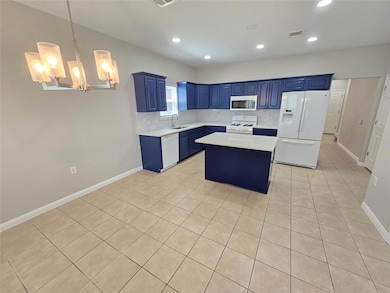 Kitchen with blue cabinetry, white appliances, a center island, light tile patterned floors, and light countertops