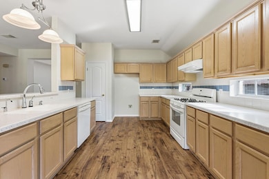 Kitchen with white appliances, dark wood-style fl
