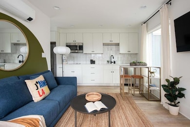 Living room with light wood-style flooring, a wall mounted AC, and recessed lighting
