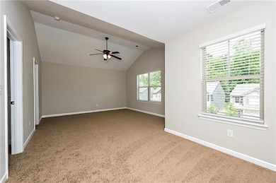 Carpeted spare room with a ceiling fan and lofted ceiling