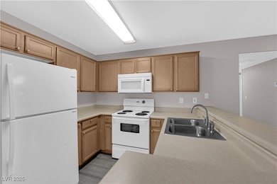 Kitchen with white appliances, a peninsula, light