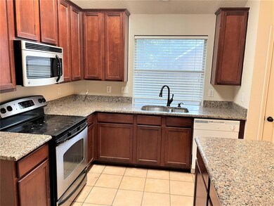 Kitchen featuring sink, appliances with stainless steel finishes, light stone countertops, and light tile patterned floors