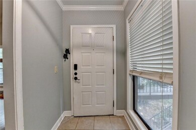 Doorway featuring ornamental molding and light tile patterned floors