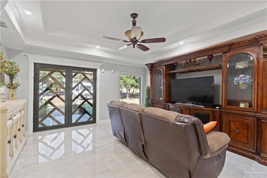 Living room featuring a raised ceiling, ceiling fan, recessed lighting, and crown molding