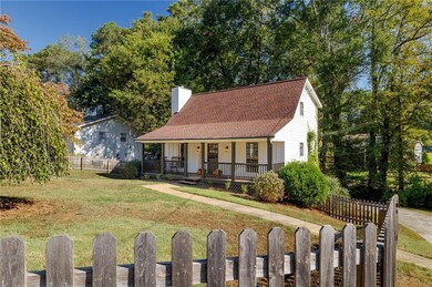 View of front of home with a porch, a shingled roof, and a chimney