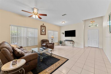 Living room features ceiling fan and tile flooring. Arched window over front door for additional natural light