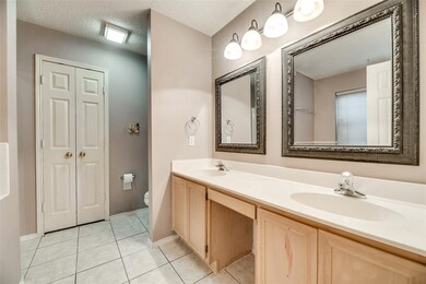 Bathroom featuring a textured ceiling, double vanity, light tile patterned flooring, and a closet