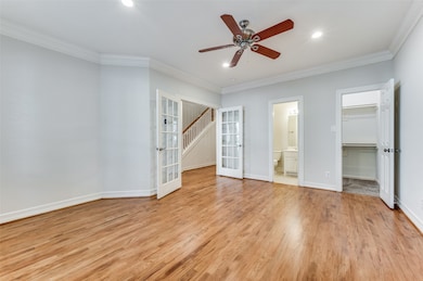 Unfurnished bedroom with french doors, light wood-style flooring, crown molding, a spacious closet, and ceiling fan