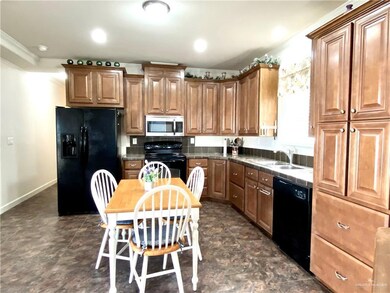 Kitchen featuring black appliances, brown cabinetry, ornamental molding, recessed lighting, and backsplash