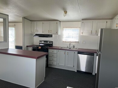Kitchen featuring stainless steel appliances, a textured ceiling, under cabinet range hood, a sink, and dark countertops