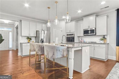 Kitchen with white cabinetry, a center island with sink, and stainless steel appliances