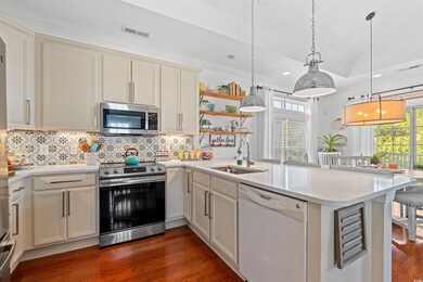 Kitchen with stainless steel appliances, light countertops, a peninsula, dark wood-style flooring, and recessed lighting