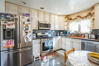 Kitchen with stainless steel appliances, granite finish floor, a sink, open shelves, and dark countertops