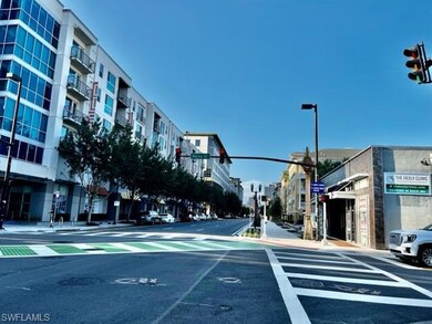 View of asphalt street with traffic lights, sidewalks, and street lights