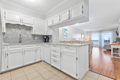 Kitchen with white cabinets, decorative backsplash, light tile patterned floors, open floor plan, and crown molding