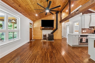 Kitchen with a wood stove, oven, wooden ceiling, light countertops, and wood walls