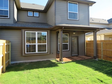Rear view of property featuring a lawn and fence