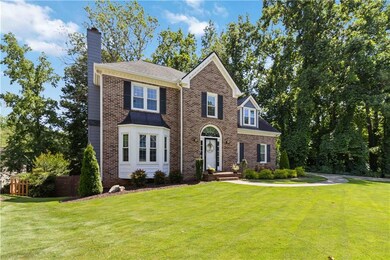 View of front of house featuring a chimney, a front yard, and brick siding