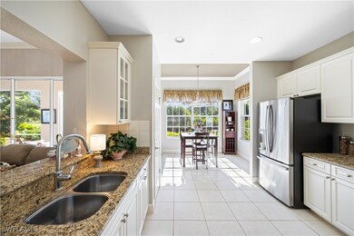 Kitchen with glass insert cabinets, stainless steel fridge, light tile patterned flooring, light stone countertops, and crown molding